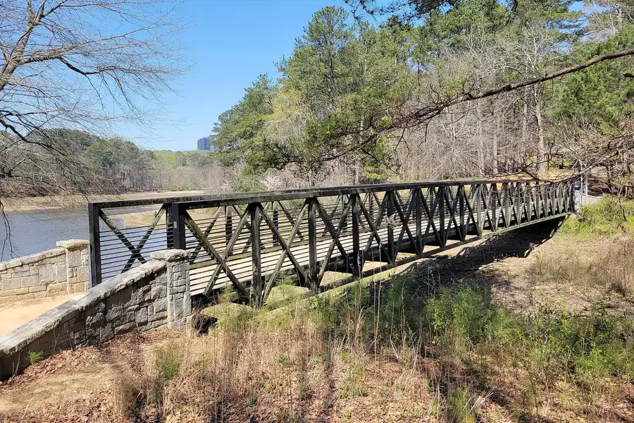 Steel footbridge over a lake edge in Murphey Candler Park in Brookhaven, Georgia