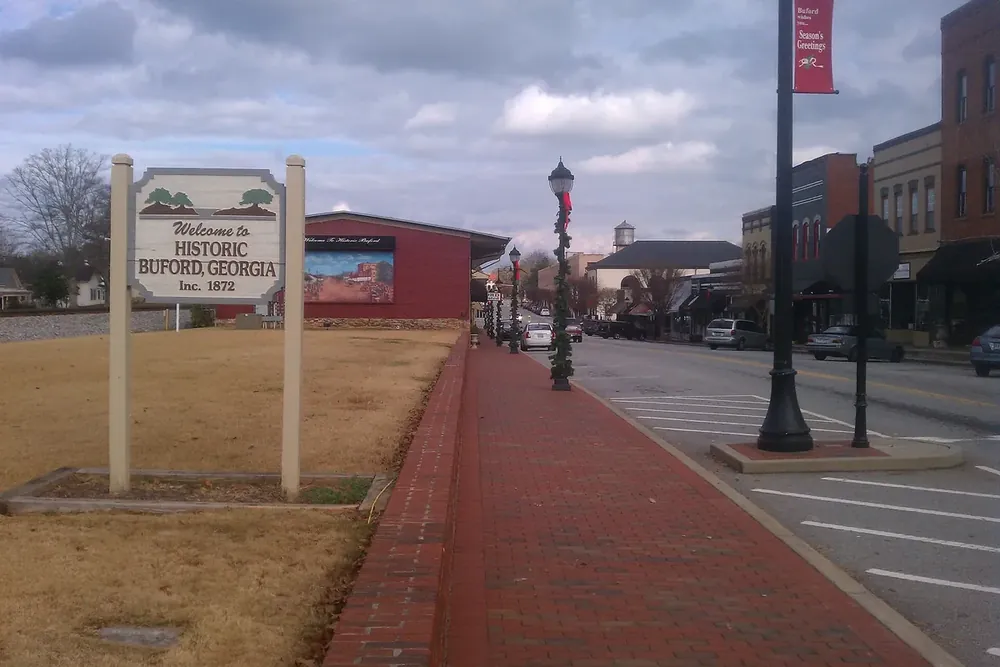 Historic Buford, Georgia welcome sign beside the Main Street sidewalk lined with brick storefronts