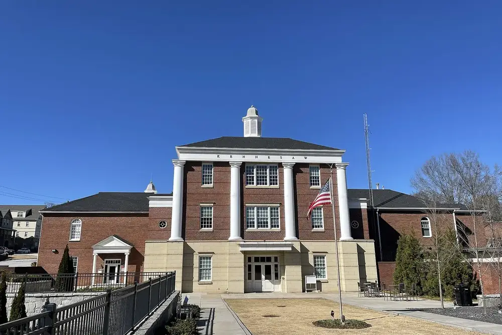 Kennesaw City Hall, a brick building with white columns and a flag, in Kennesaw, Georgia