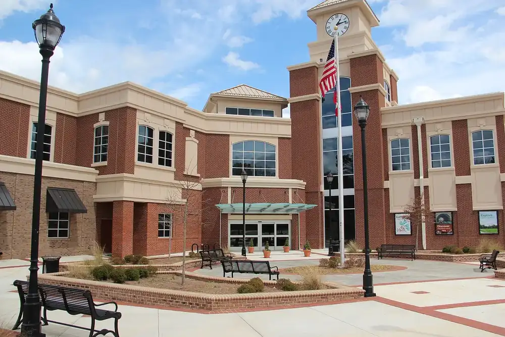 Lilburn City Hall, a brick building with a clock tower and flag, facing a plaza in Lilburn, Georgia