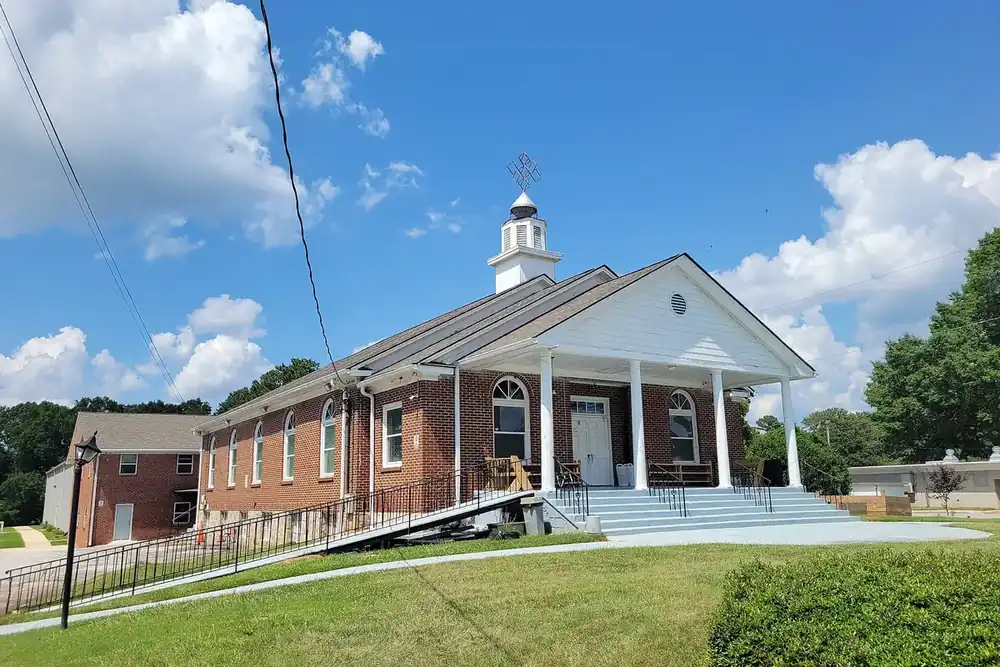 White-columned brick church with a small steeple on a green lawn in Redan, Georgia