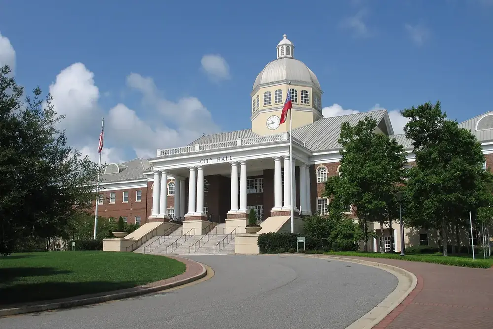 Roswell City Hall with a domed cupola and white columns beside the curved entrance drive in Roswell, Georgia