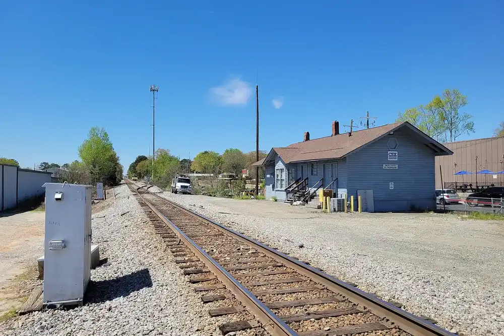Small blue Tucker Depot beside railroad tracks on a clear day in Tucker, Georgia